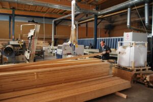 Hombre trabajando en una fábrica de madera con maquinaria y tablones
