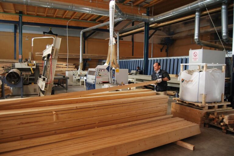 Hombre trabajando en una f&aacute;brica de madera con maquinaria y tablones