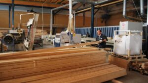 Hombre trabajando en una f&aacute;brica de madera con maquinaria y tablones