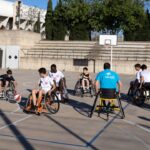 Grupo de jóvenes en sillas de ruedas jugando baloncesto en un evento de voluntariado.
