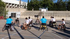 Grupo de j&oacute;venes en sillas de ruedas jugando baloncesto en un evento de voluntariado.