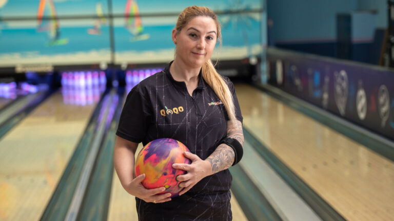 Cristina, jugadora de bolos, sosteniendo una bola en la pista.