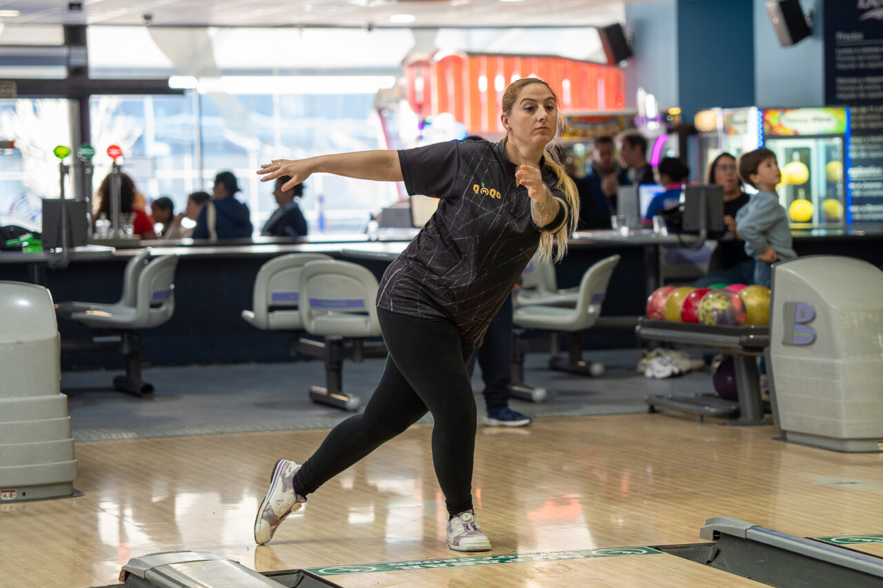 Mujer lanzando una bola en una pista de bolos