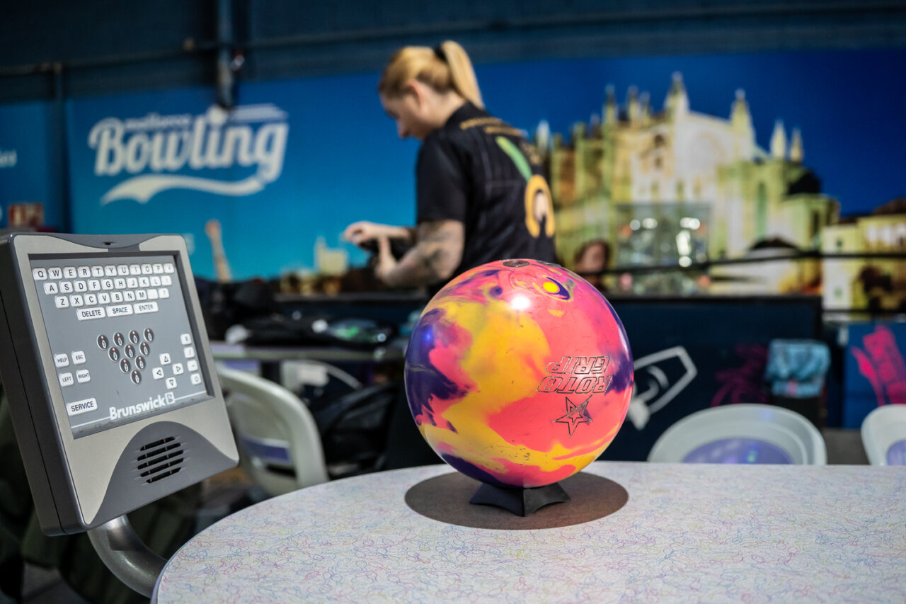 Bola de bolos colorida en una mesa con jugadora de fondo