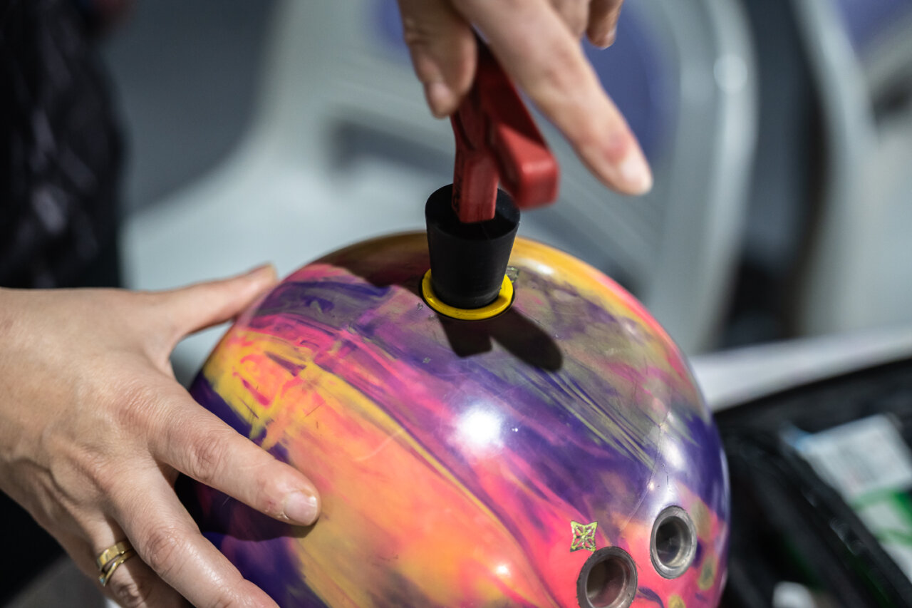 Mano sosteniendo una bola de bolos con colores vibrantes