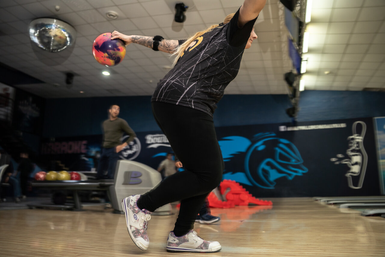 Mujer lanzando una bola de bolos en una bolera