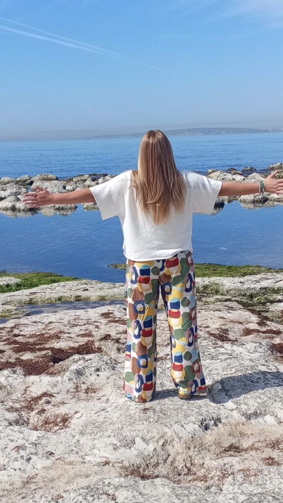 Mujer de espaldas con brazos abiertos frente al mar