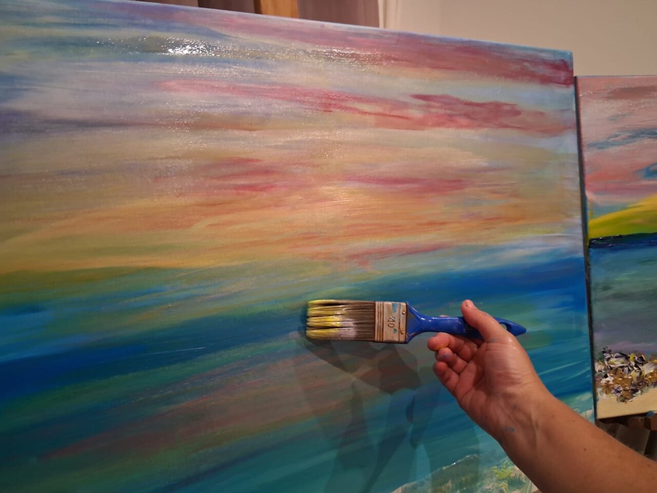Mano pintando un paisaje en un lienzo con brocha
