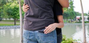 Pareja abraz&aacute;ndose en un parque, con un gesto sospechoso.