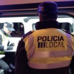 Agente de la polic&iacute;a local de Palma frente a un furg&oacute;n policial en la noche.