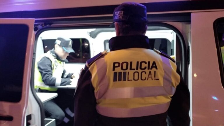Agente de la polic&iacute;a local de Palma frente a un furg&oacute;n policial en la noche.
