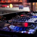 Cabina de DJ con equipo de mezcla y luces en un evento electrónico