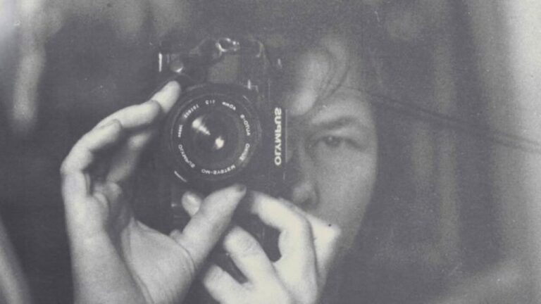 Persona sosteniendo una cámara Olympus mientras se toma una selfie