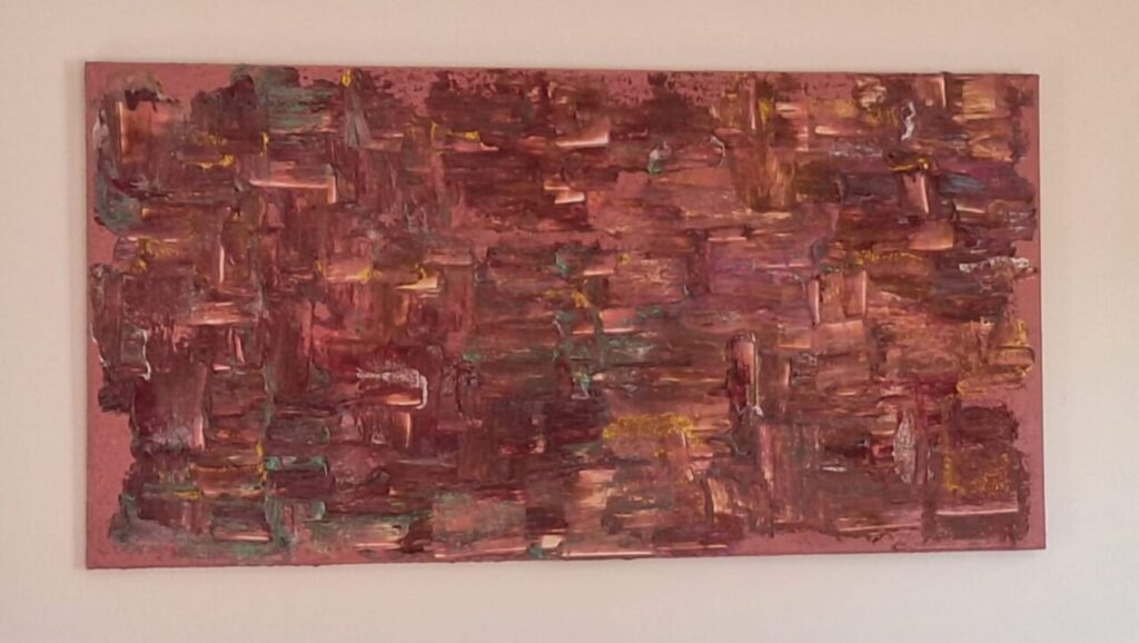 Pintura abstracta en tonos rojos y amarillos en una pared.