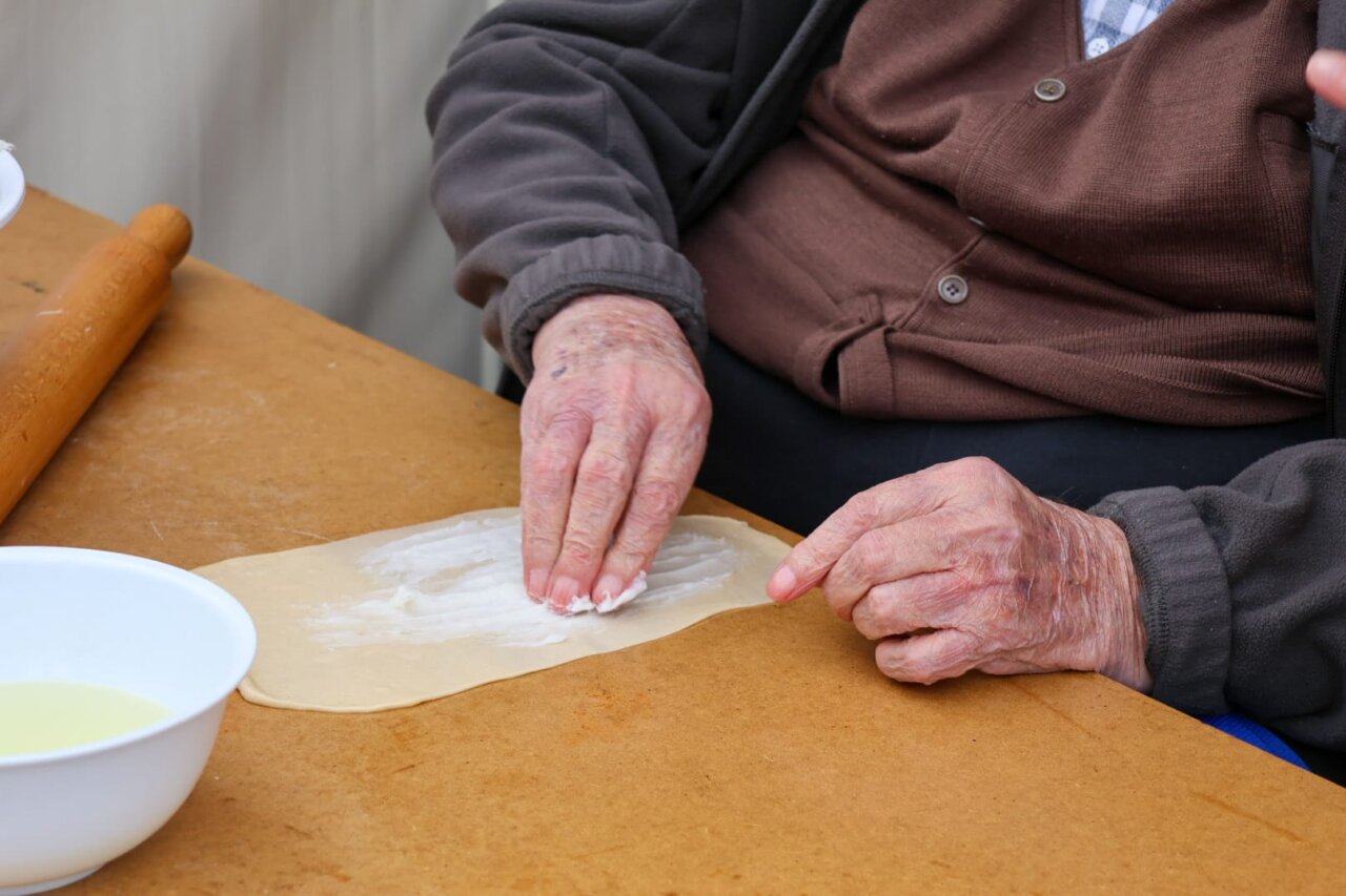 Manos de una persona preparando una ensaimada en una feria local