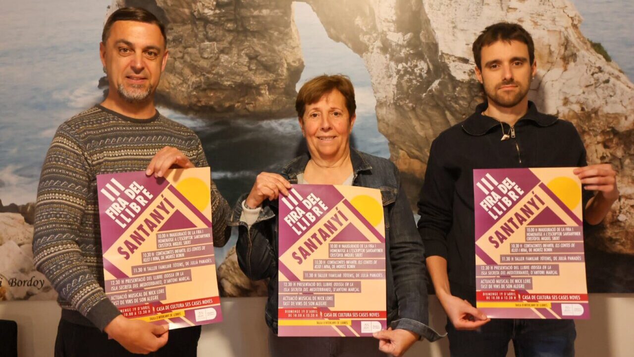 Tres personas sosteniendo carteles de la III Fira del Llibre en Santany&iacute;