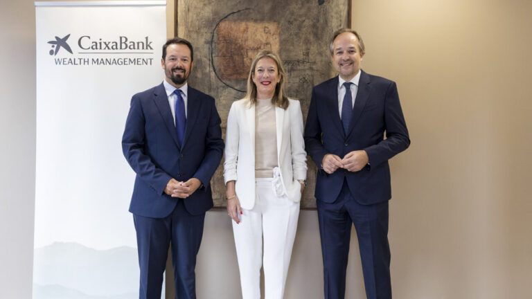 Tres personas posando junto a un cartel de CaixaBank Wealth Management