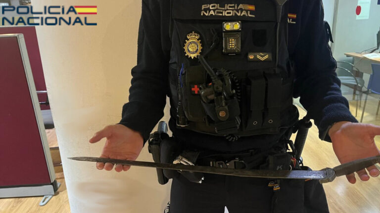 Agente de polic&iacute;a mostrando un arma intervenida tras una agresi&oacute;n a una pareja.