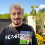Jaime Roig de Diego sosteniendo su novela en un entorno ajardinado