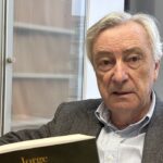 Jorge Dezcallar sosteniendo su novela Pez Negro en un ambiente interior
