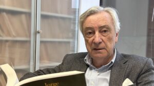 Jorge Dezcallar sosteniendo su novela Pez Negro en un ambiente interior