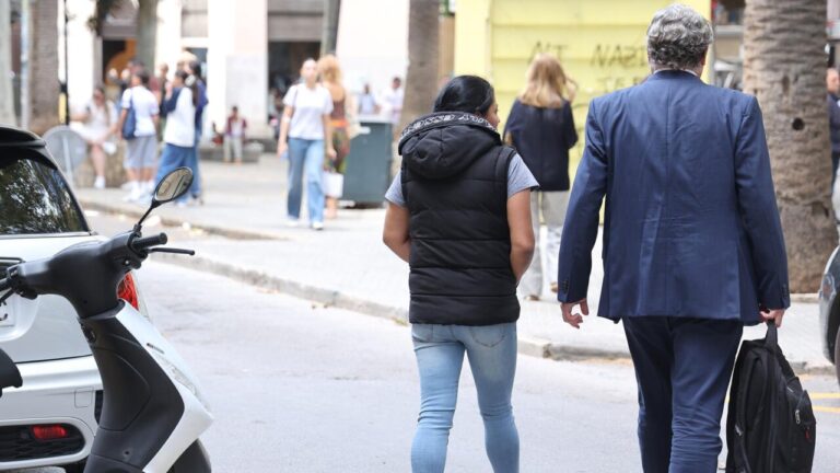 Mujer caminando junto a un hombre en una calle de Porto Cristo