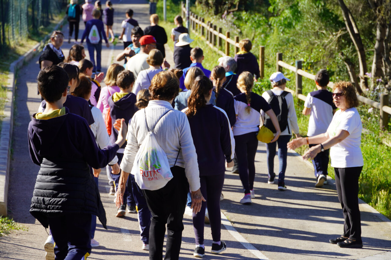 Grupo de ni&ntilde;os y personas mayores caminando juntos por un sendero