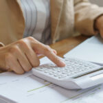 Persona usando una calculadora y un ordenador para la declaraci&oacute;n de la renta