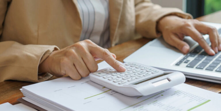 Persona usando una calculadora y un ordenador para la declaraci&oacute;n de la renta