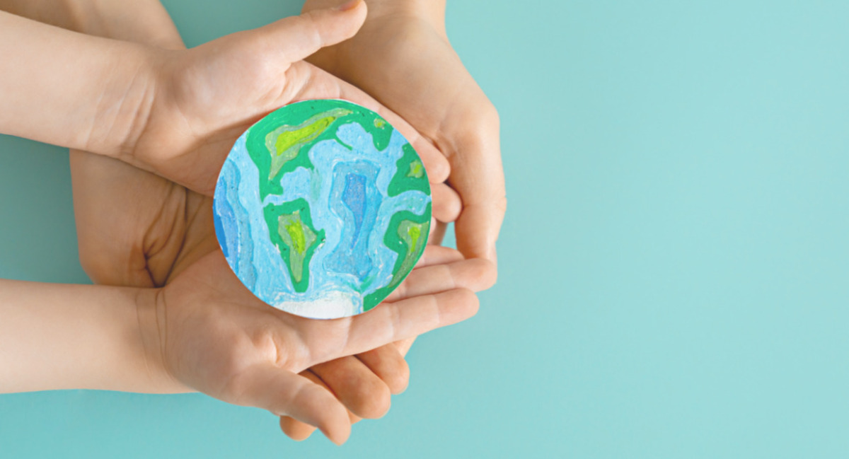 Manos sosteniendo un modelo del planeta Tierra pintado a mano
