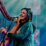 Moya Brennan tocando el arpa y cantando en un escenario iluminado