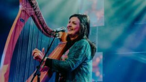 Moya Brennan tocando el arpa y cantando en un escenario iluminado