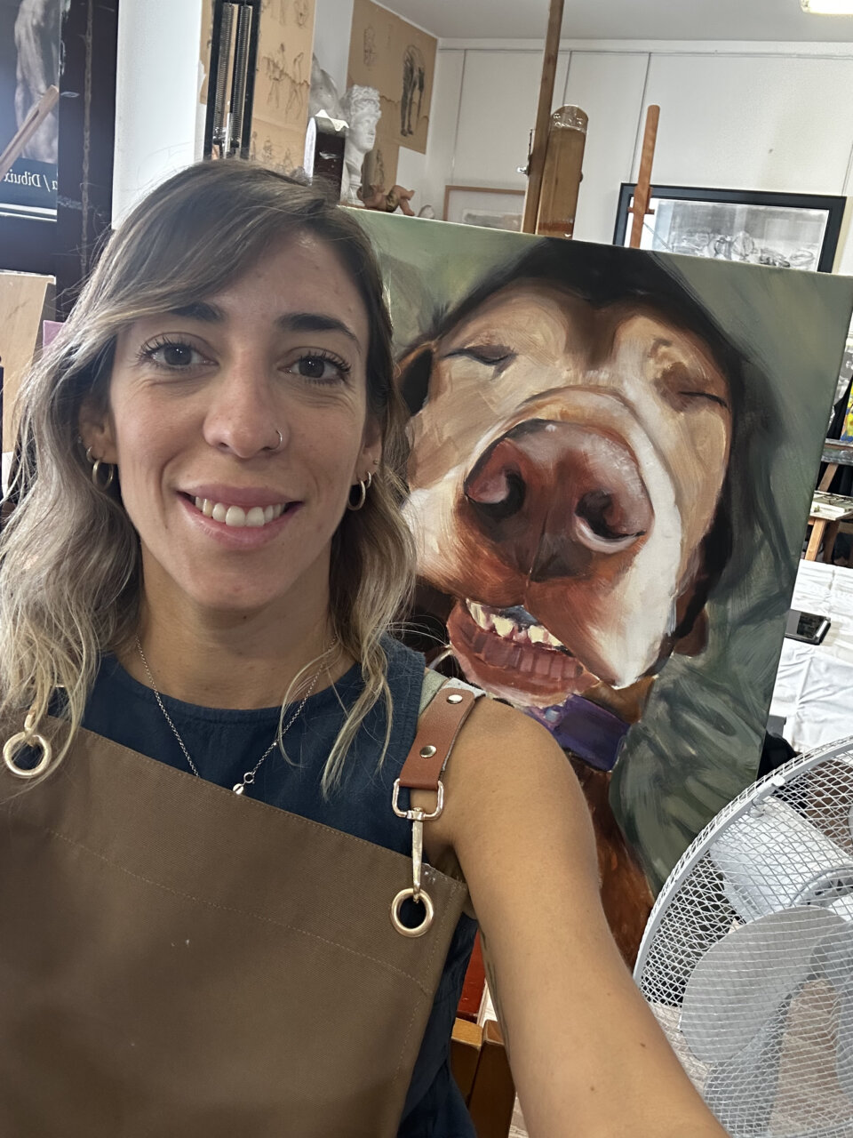Natalia Aguilar sonriente en su taller con un retrato de un perro