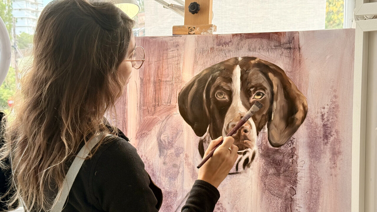 Artista Natalia Aguilar pintando un retrato de un perro en su taller