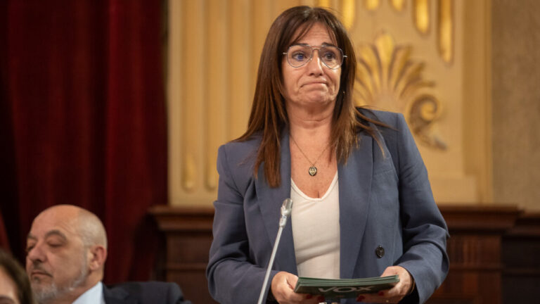 Mujer con chaqueta en el parlamento, sosteniendo un documento.