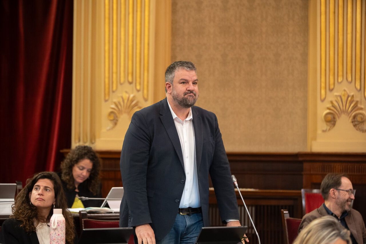 Hombre de pie en el parlamento con otros asistentes en el fondo
