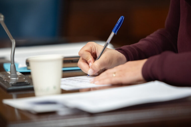 Mano escribiendo en un documento con bol&iacute;grafo en una mesa