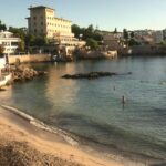 Vista de la playa Bugambilia en Calvià con personas disfrutando del agua.