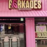 Fachada del restaurante Porkades con colores rosa y letrero visible