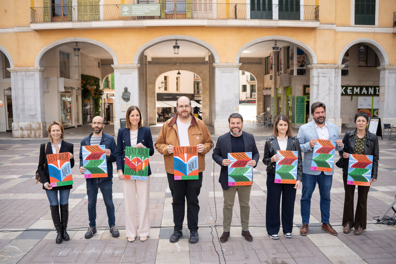 Grupo de personas presentando la Diada de Sant Jordi con carteles coloridos