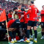 Jugadores del RCD Mallorca celebrando un gol en el estadio con aficionados al fondo.