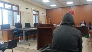 Sala de juicio con un hombre de espaldas y jueces al fondo
