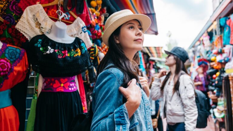 Turista explorando un colorido mercado lleno de ropa tradicional