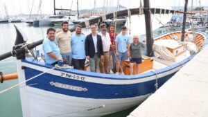 Grupo de personas junto a la barca de bou Rafael en el puerto