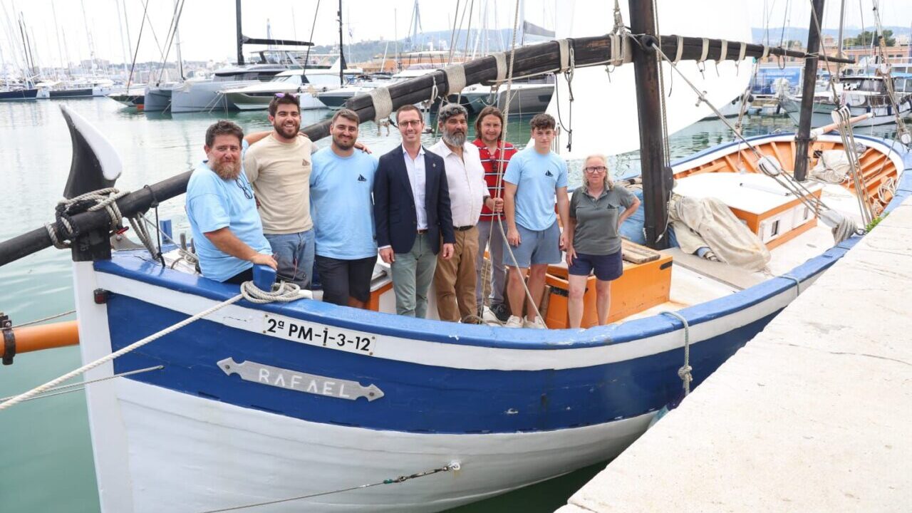 Grupo de personas junto a la barca de bou Rafael en el puerto