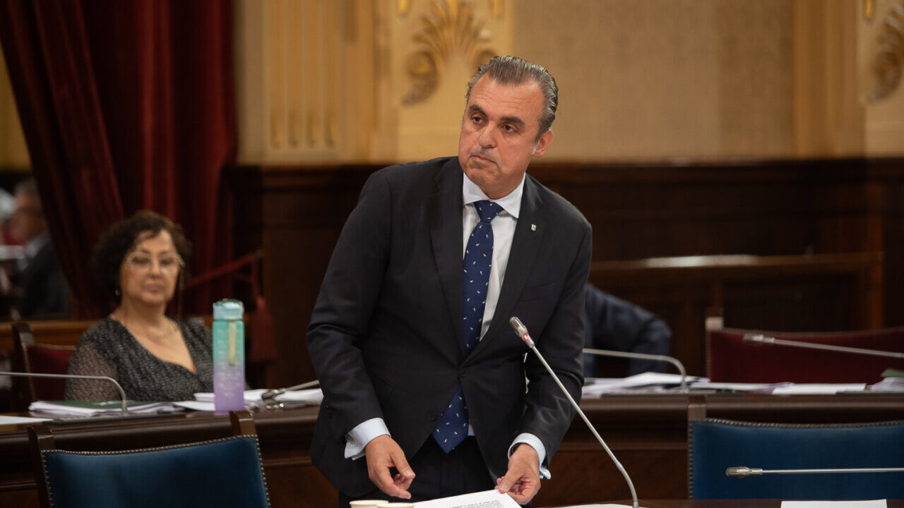 Hombre de pie en el parlamento durante una sesi&oacute;n con documentos en la mano.
