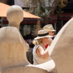 Dos mujeres con sombreros en un entorno urbano soleado