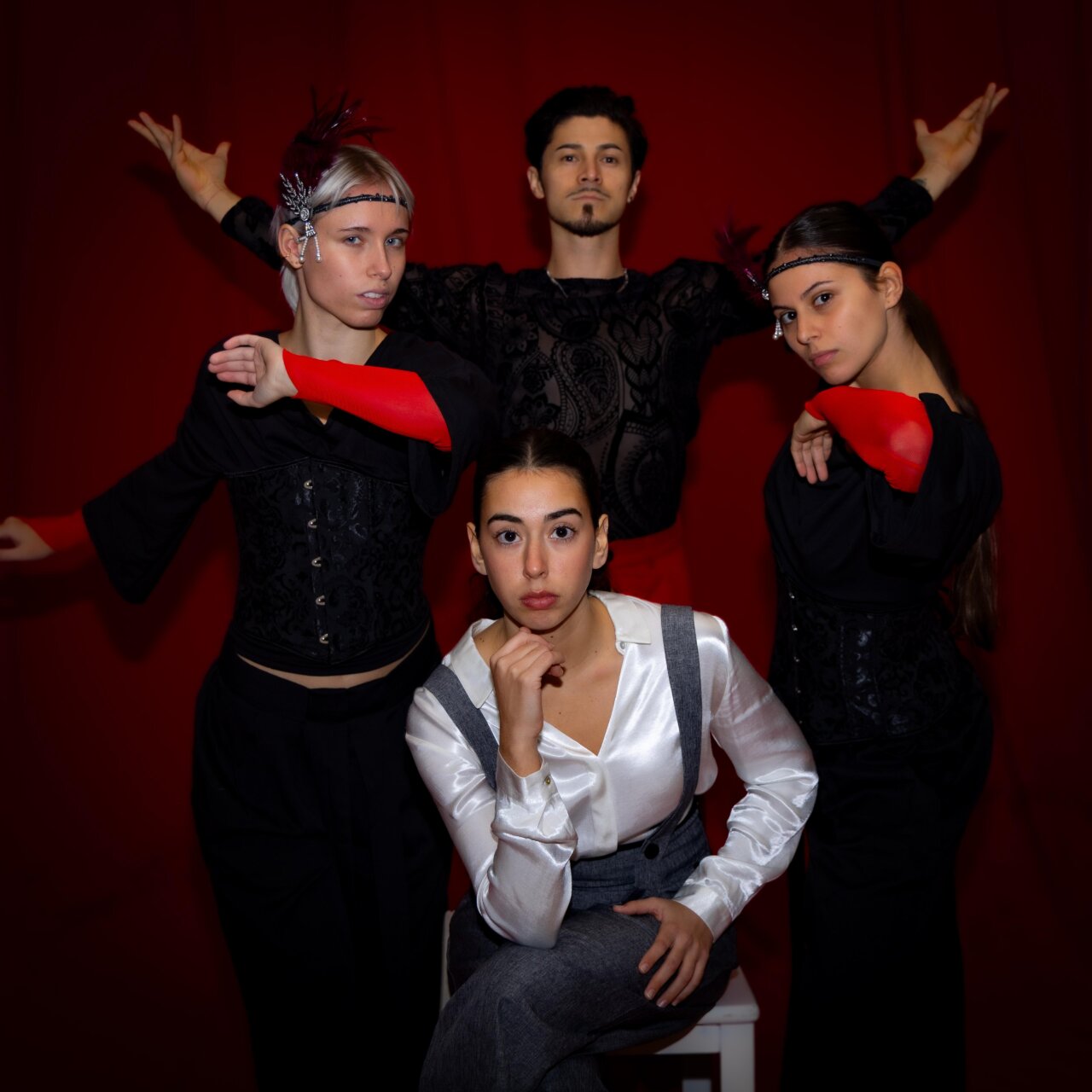 Cuatro personas posando en un fondo rojo con vestimenta elegante.