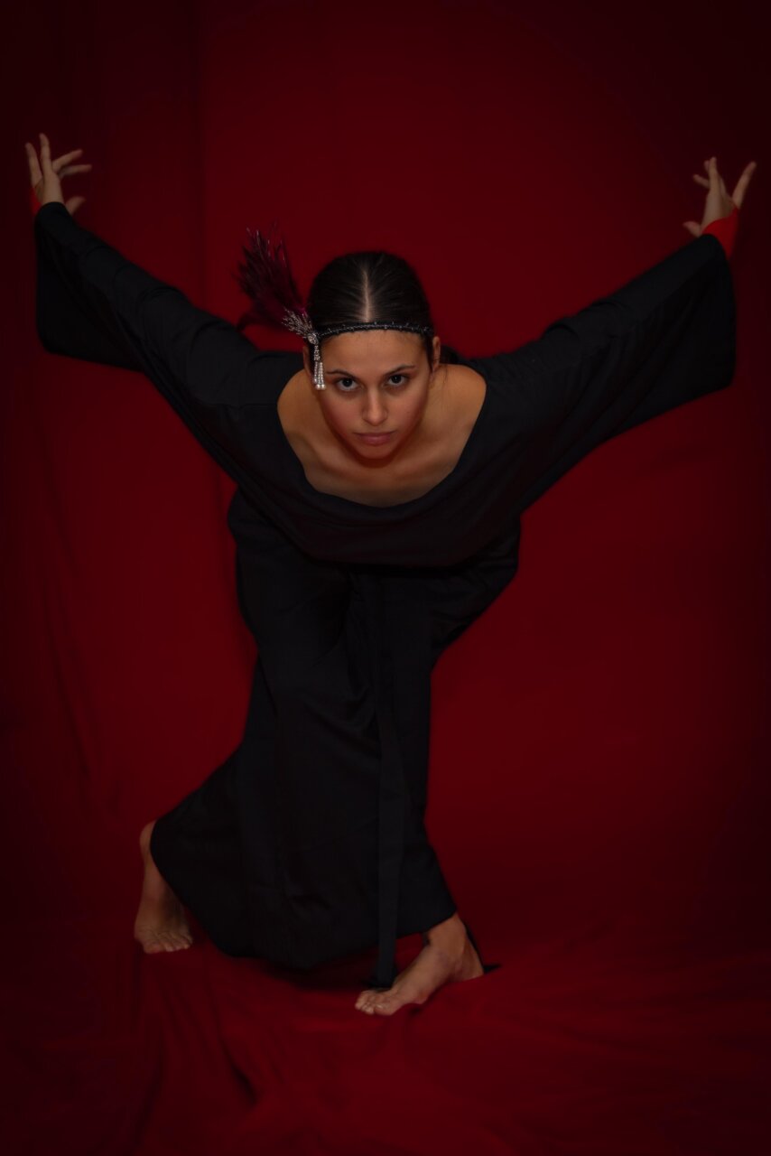 Mujer en pose dramática con fondo rojo y vestimenta negra