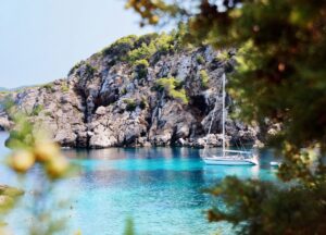 Barco de alquiler en aguas cristalinas de Ibiza rodeado de rocas